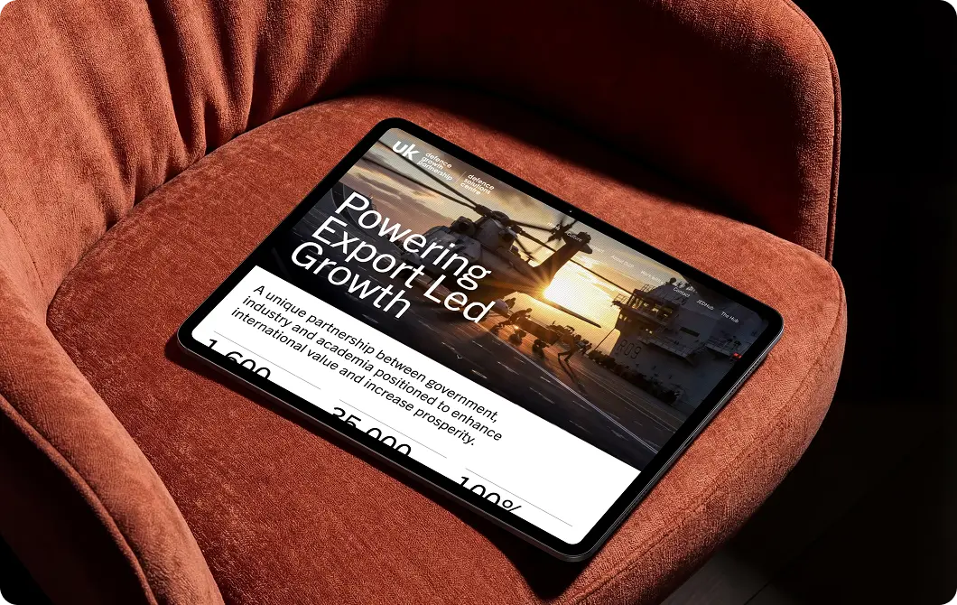 Powering Growth website page displayed on a tablet resting on an orange sofa