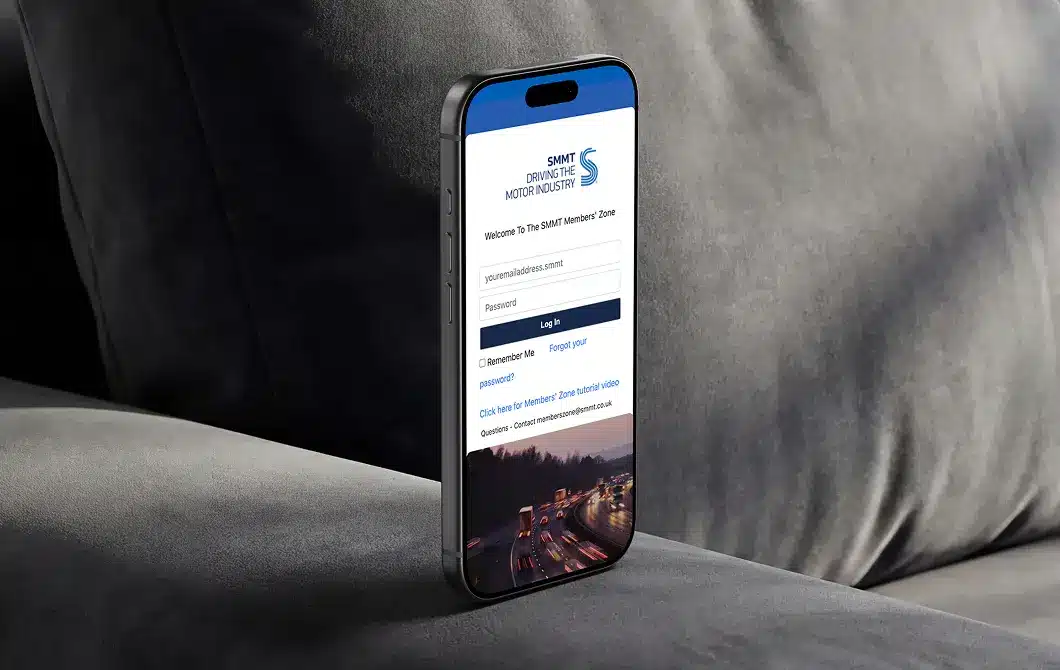 SMMT login page displayed on a smartphone held against a textured grey background