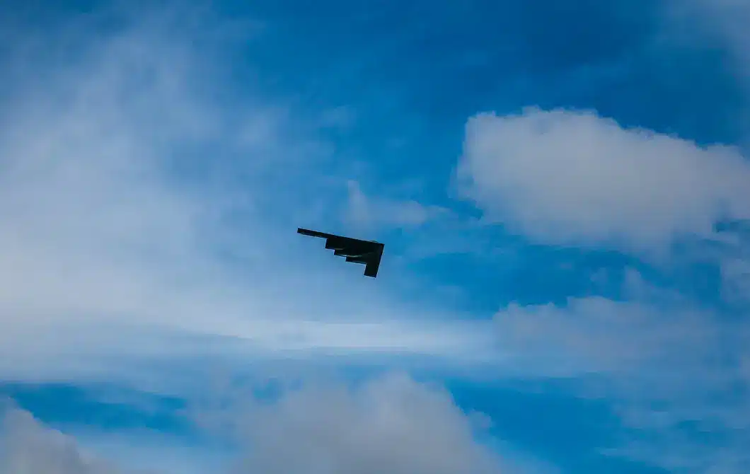 Military aircraft flying against a bright blue sky with light cloud